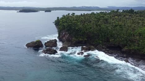 Ocean-waves-crashing-on-rugged-tropical-shore,-Aerial