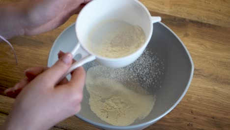 woman sifts flower into a bowl