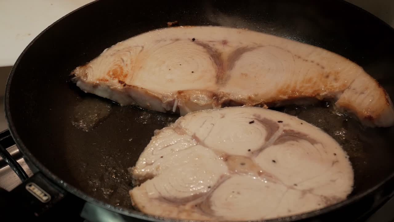 Tilberedning af sværdfiskebøffer, der syder på en varm pande, en frisk havfråde.