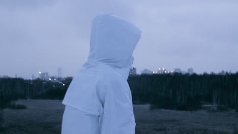persona con capucha blanca viendo el paisaje de la ciudad al crepúsculo