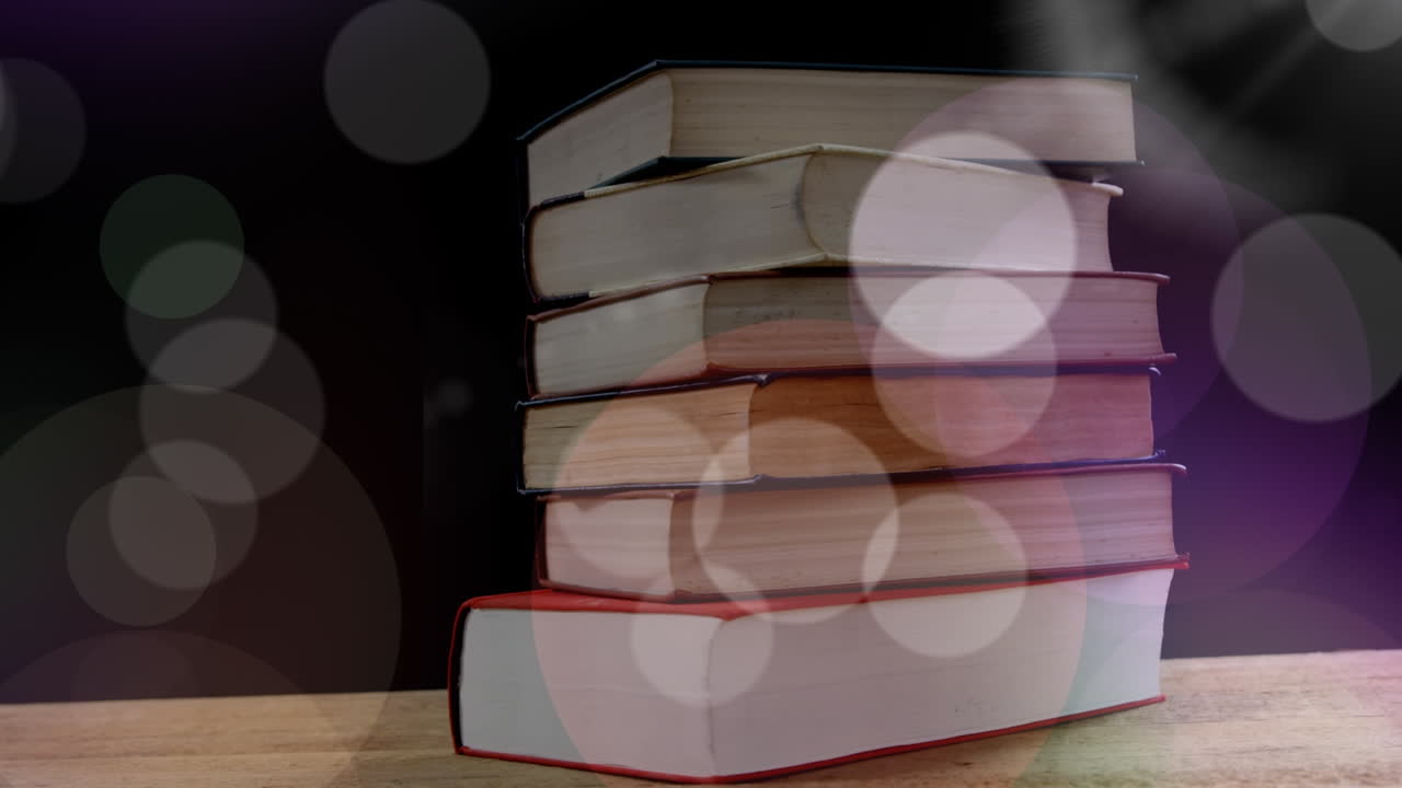 검은 바탕에 있는 책 위에 있는 빛의 반점들의 애니메이션