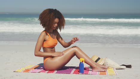 Afroamerikanische-Frau,-Die-Am-Strand-Sonnenschutzmittel-Aufträgt