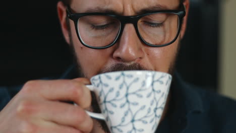 rostro masculino vacilante en probar la taza de café moviendo la cabeza de cerca