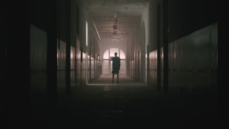 a bald man walks on the empty hospital corridor at night