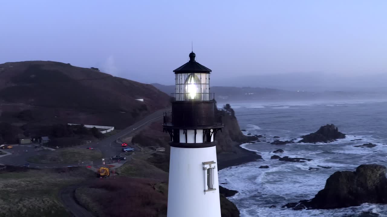 faro principal de yaquina en la costa de oregon al atardecer, disparo de arco aéreo