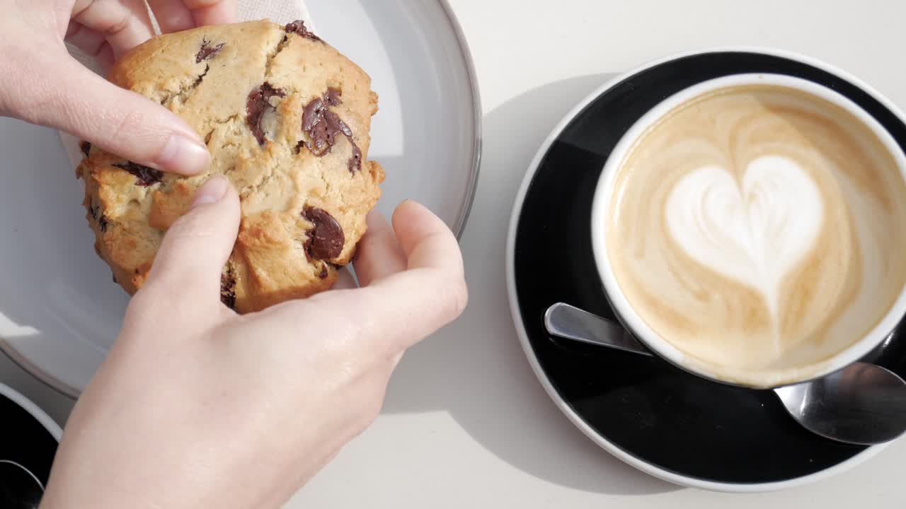 Delicious cookie being torn apart with gooey chocolate and a coffee with a heart-shaped foam design