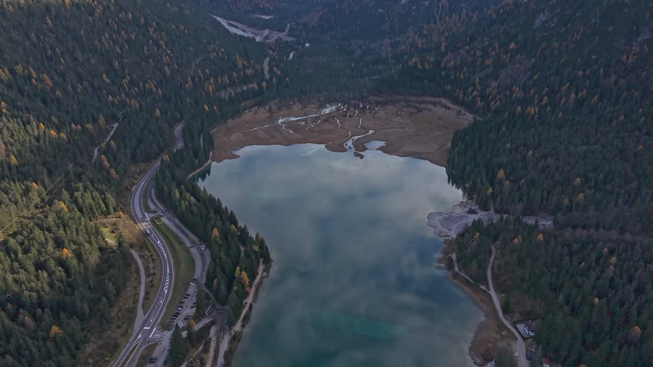 Veduta aerea del Lago di Dobbiaco con acqua cristallina e foreste dorate, Dolomiti, Italia
