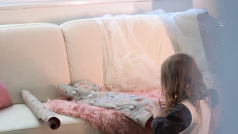 young child wrapping a gift for christmas or child's birthday party