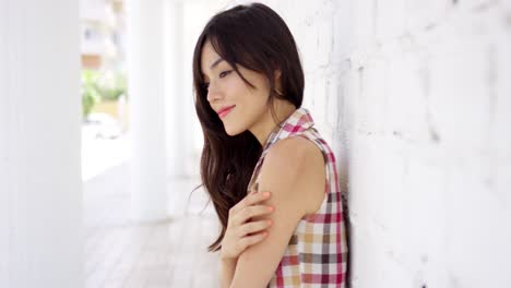 Woman-leaning-against-brick-wall-painted-white