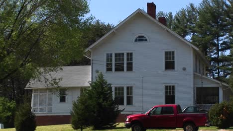 camera zooms in to a window on the second story of a white farmhouse