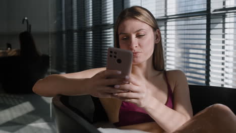 woman relaxing in a modern bathtub with smartphone