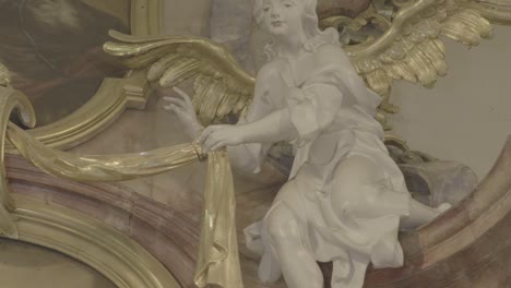 camera pans to the sculpture of a white angel with golden wings on a baroque altar