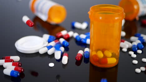 muchas píldoras recetadas, medicamentos y cápsulas que caen a cámara lenta en una botella de medicina de farmacia naranja