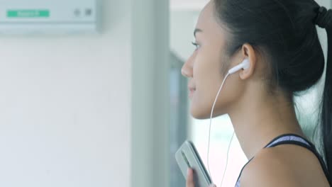 asian girl running on the treadmill in the gym with earphones