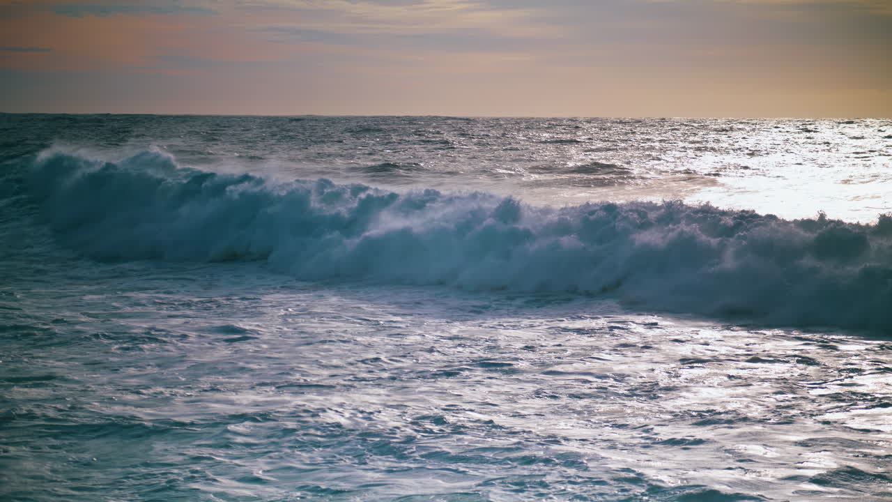 las olas espumosas rodando la orilla del amanecer en cámara lenta. hermosa vista nocturna de la costa.