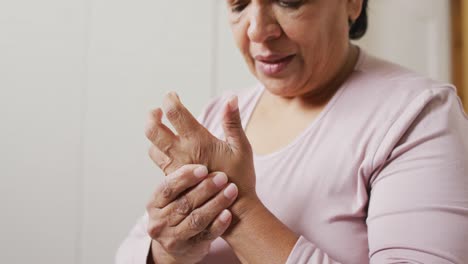 Close-up-of-african-american-senior-woman-holding-her-hand-in-pain-at-home