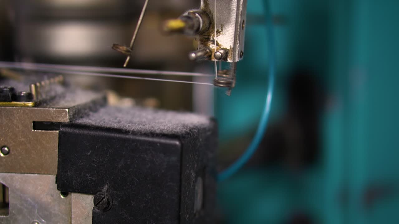 Primo piano di una macchina automatica che stira il filo in una fabbrica di abbigliamento.