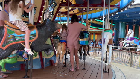 children riding carousel horses on merry-go-round at amusement park