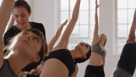 beautiful yoga woman instructor teaching reverse warrior pose meditation with group of multiracial women enjoying healthy lifestyle exercising in fitness studio at sunrise