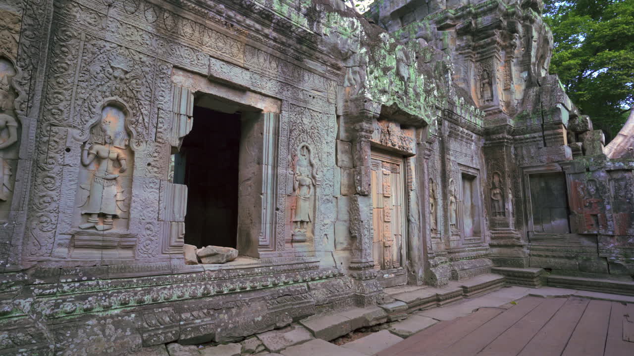 Exterior of stone Angkor temple entrance with steps and cracked columns, wide angle establishing static, no people