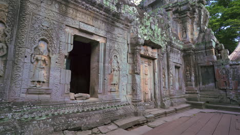 exterior of stone angkor temple entrance with steps and cracked columns, wide angle establishing static, no people