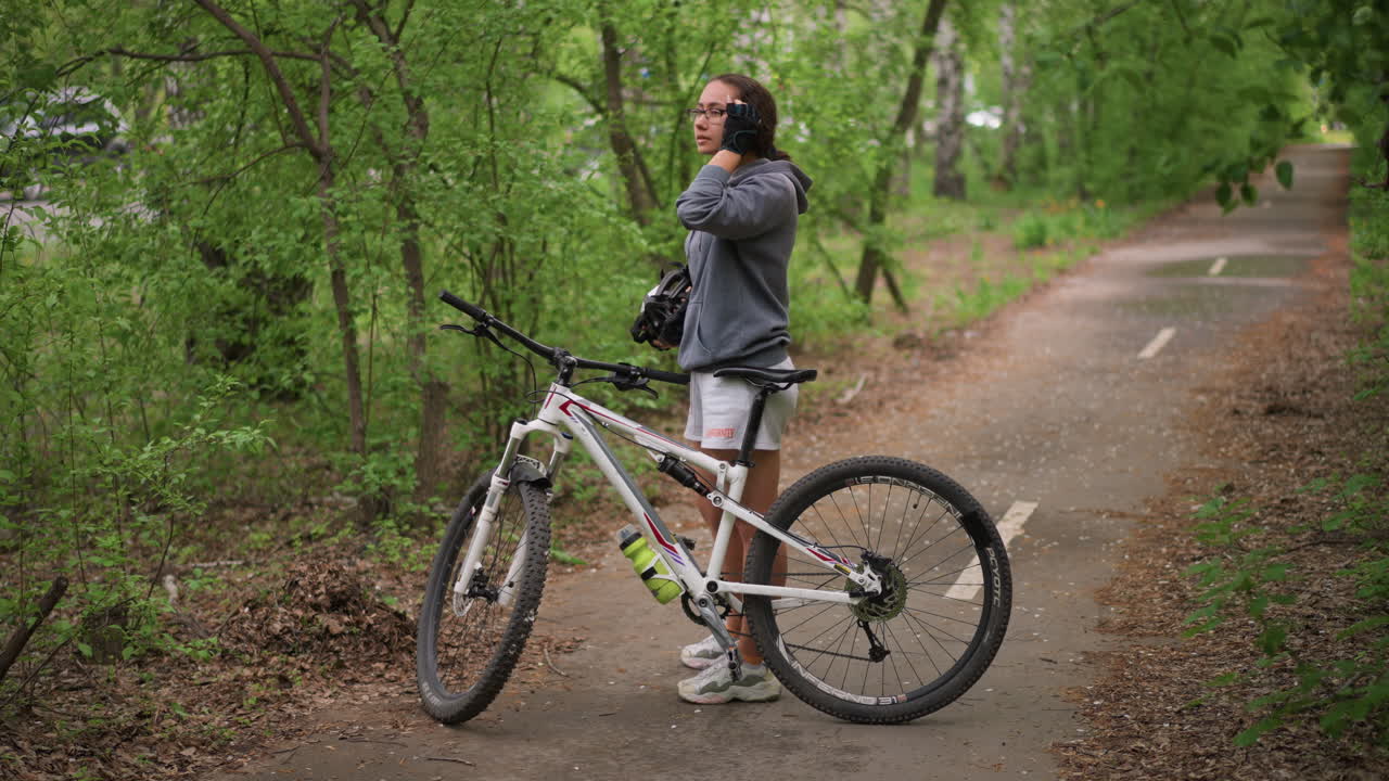 Ciclista de montaña seguro de sí mismo en una senda frondosa del bosque, ciclista casual posa con orgullo con su bicicleta de montaña entre árboles, ciclista relajado de pie con confianza junto a su bicicleta de montaña en un entorno de bosque exuberante