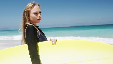 mujer sosteniendo una tabla de surf en la playa