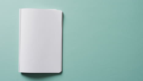 close up of open blank book with copy space on green background in slow motion