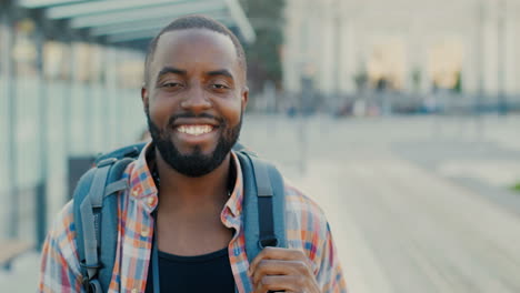 close-up view of african american man traveller smiling and looking at camera at bus station