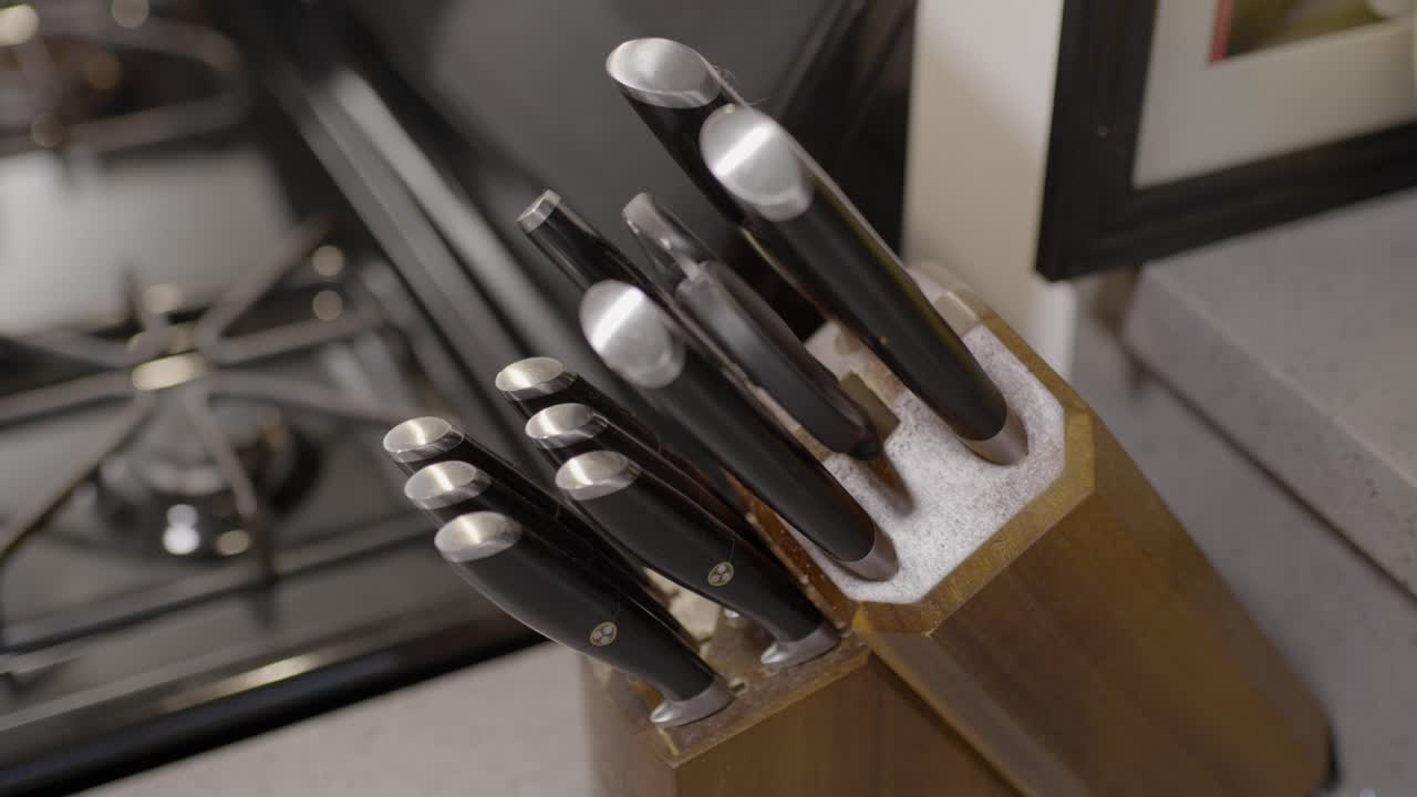 Medium kitchen knife being pulled out from a knife block and then put back in. Male hand pulling out a knife. Kitchen knife being pulled out