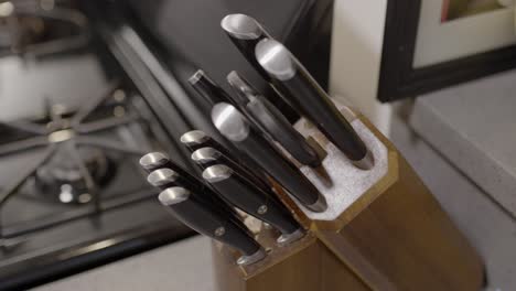 medium kitchen knife being pulled out from a knife block and then put back in. male hand pulling out a knife. kitchen knife being pulled out