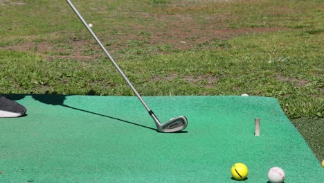 el club de golf golpeando la pelota en la alfombra de práctica