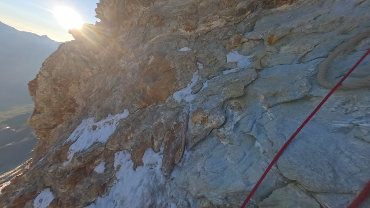 First-person POV of a climber ascending the iconic Matterhorn at sunrise on a crystal-clear bluebird day. Captured on GoPro for an immersive, realistic mountaineering experience above the clouds
