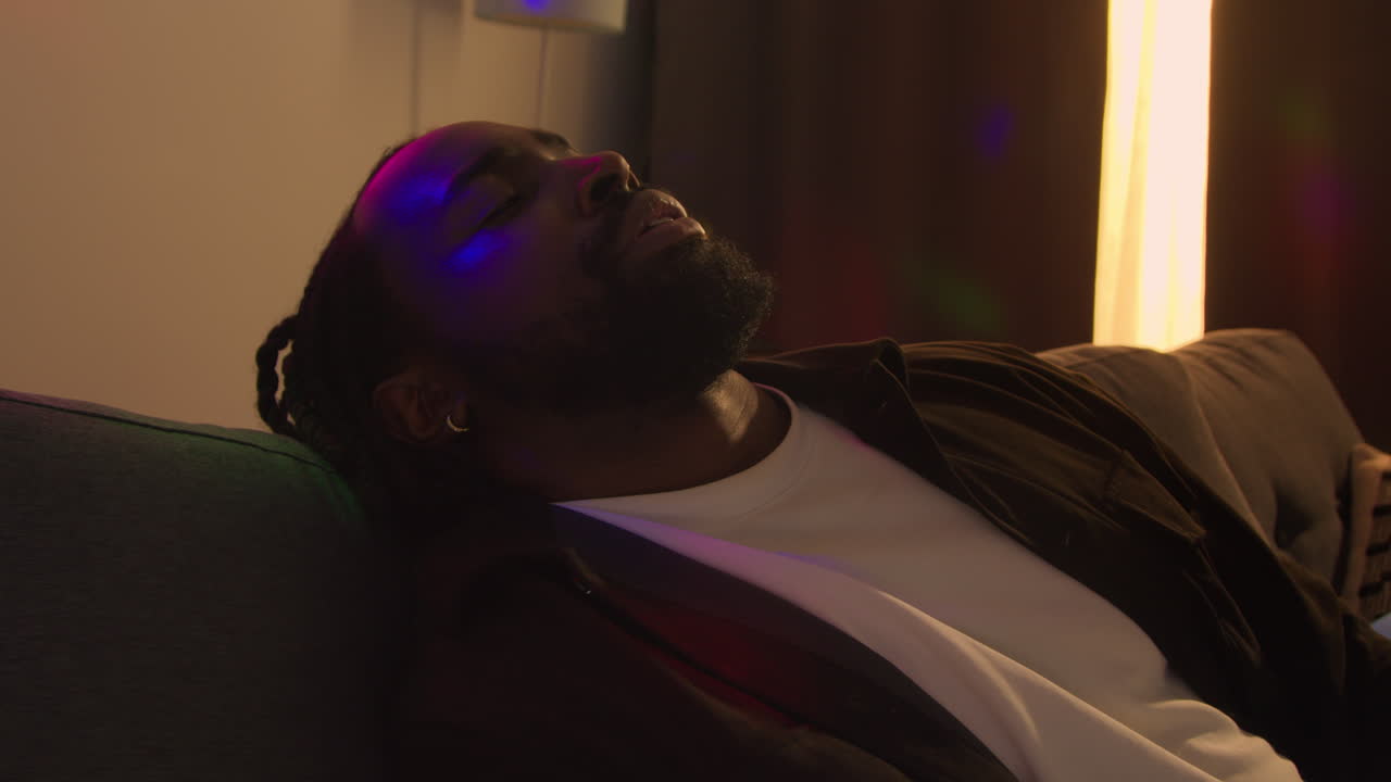 hombre sentado en el sofá recuperándose de beber alcohol en una fiesta de casa sufriendo de resaca