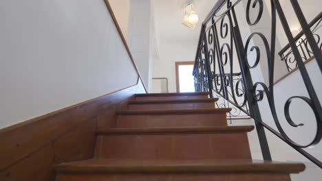 slow dolly shot up a staircase within a villa with metal decorative railings