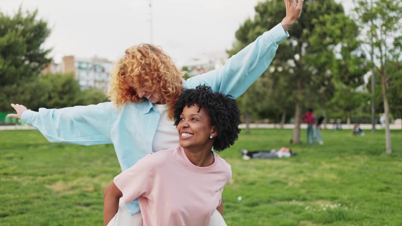Joyful Friends Laughing While One Gives a Piggyback Ride in a Park