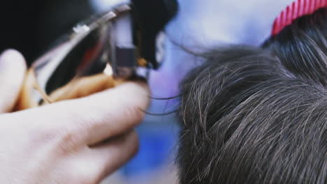 hairdresser does trendy haircut to young customer in salon