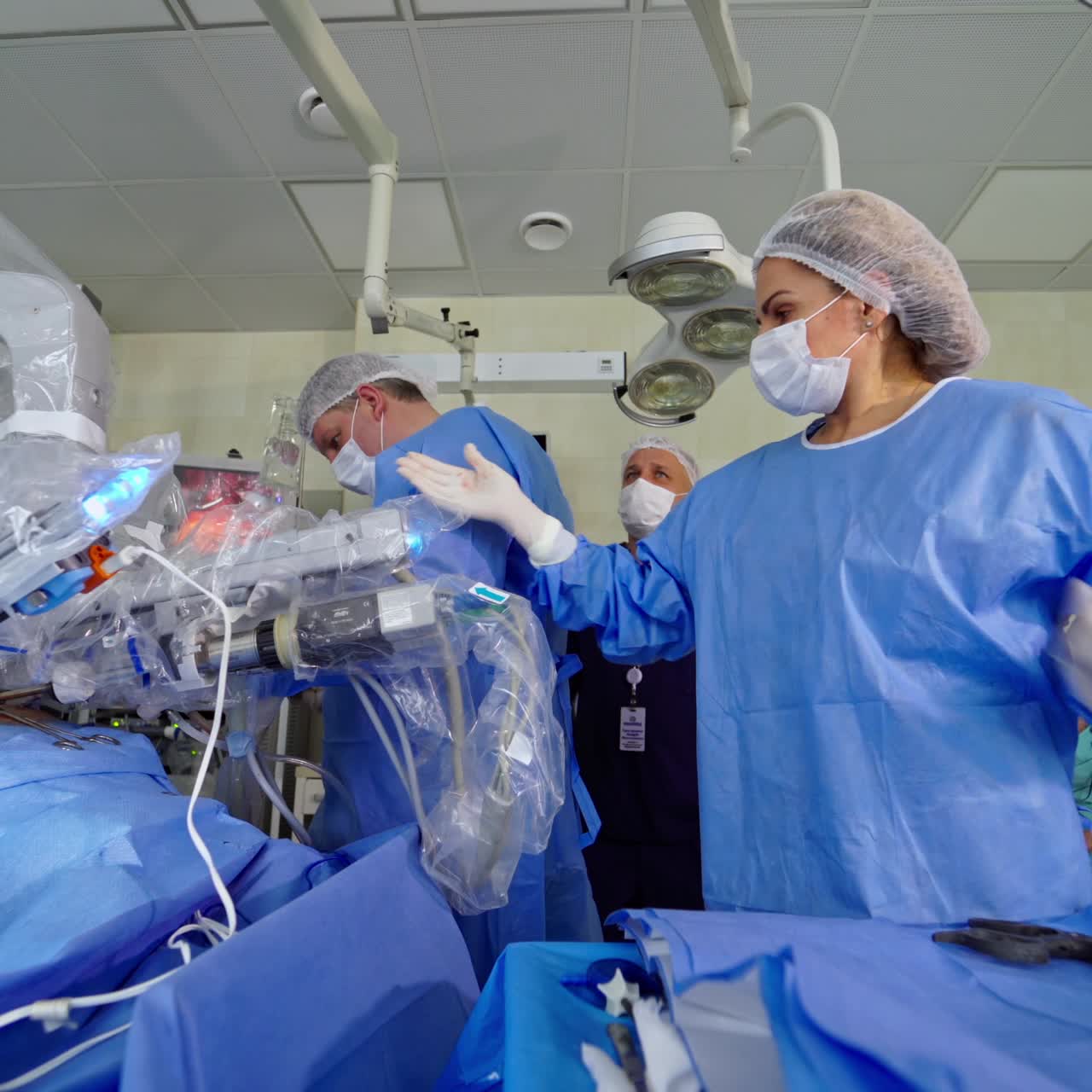 Surgical room in hospital with robotic technology equipment. Group of surgeons work near machine arm in futuristic operating room. Minimal invasive surgery with medical robot