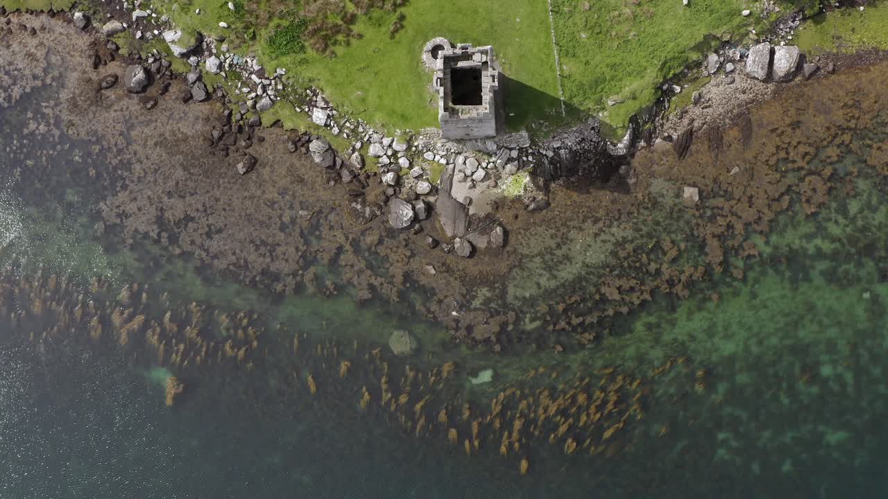 Aerial top down perspective of Grace O'Malley's Towerhouse and kelp forest of achill island in ocean by ireland