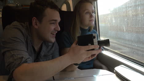 young couple with retro video camera in train