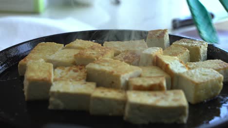 close up steam coming out of tofu being cooked on pan special ingredients to cook a meal two cans of beans rice plantain avocado red onion and cilantro