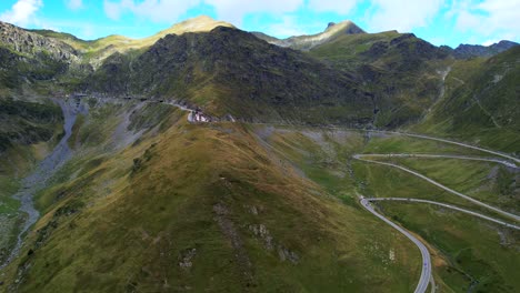 aerial trucking pan overview of winding transfagarasan serpentine road cutting through vibrant green hillside
