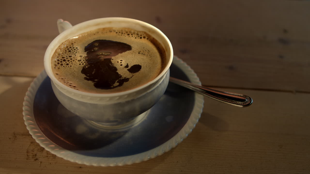 los dedos dejan caer dos terrones de azúcar en una taza de café recién hecha, a cámara lenta