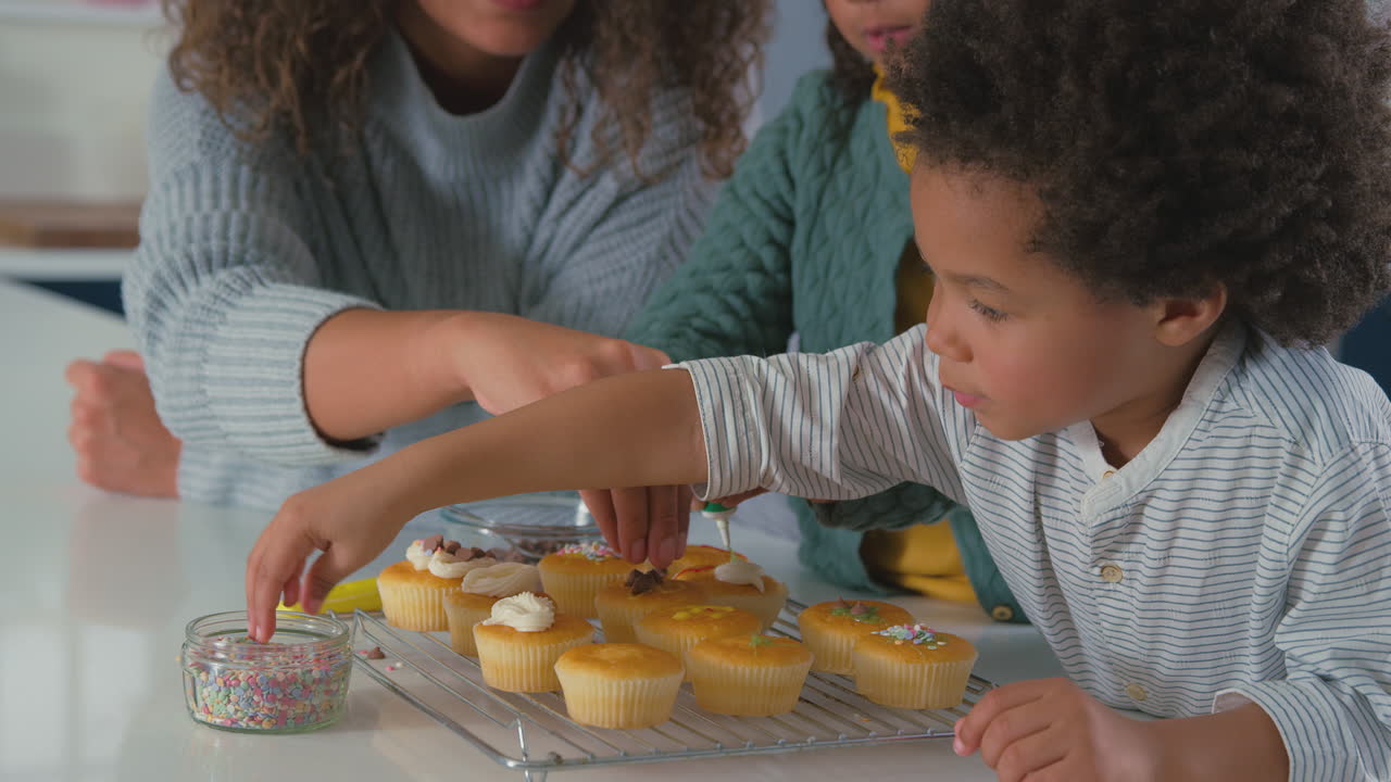 부 에서 어머니 와 자녀 들 이 함께 컵케이크 를 장식 하는 모습