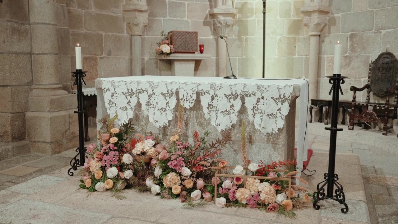 Pink and peach flower installation at a stone church altar with lace cloth