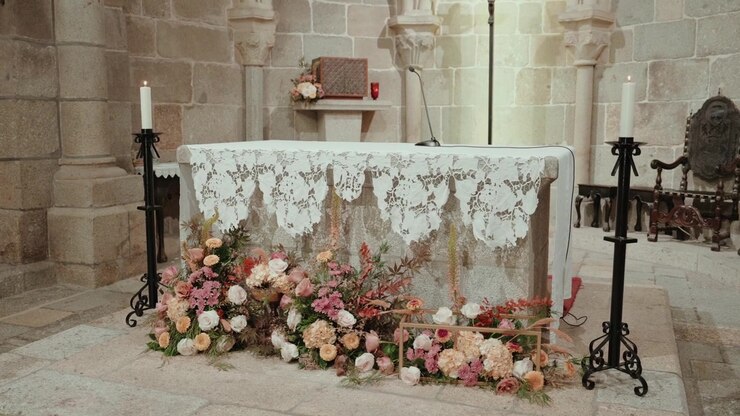 Pink and peach flower installation at a stone church altar with lace cloth