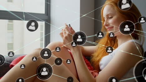 iconos de perfil que se conectan con líneas sobre mujer caucásica rubia que usa un teléfono inteligente en el sofá