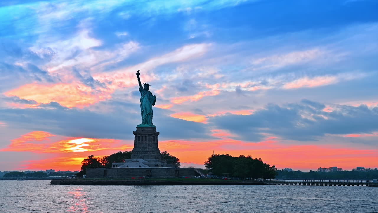 Moving on boat along the Liberty Island. Statue of Liberty at the backdrop of colorful sky at sunset