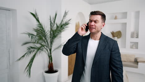serious caucasian male speaks on the phone. man changes into video call looking at his smartphone. blurred backdrop.