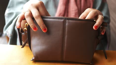 a woman's hand holding a brown leather bag